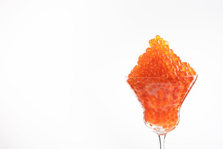 Red caviar in a glass wine glass. Close-up. Salmon caviar. Delicacies. Delicious food. The concept of a luxurious life. A useful omega. An expensive snack.Space for text. White background.の写真素材