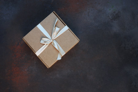 The cardboard holiday box is tied with a ribbon. Festive packaging. A gift for the holiday. With space to copy.View from above.Dark background.の写真素材