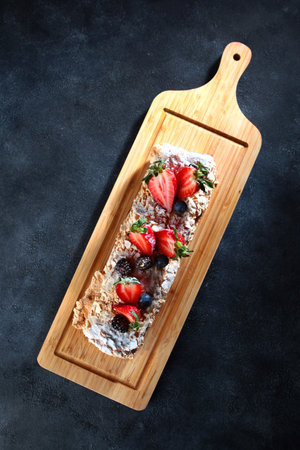 Meringue roll with strawberries on a wooden board. Flat lay.Top view.Copy space.の写真素材