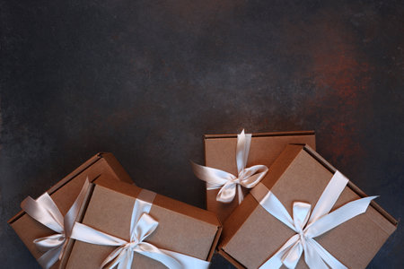 Gift delivery. The cardboard holiday box is tied with a ribbon. Festive packaging. A gift for the holiday. With a space to copy. View from above.Dark background.の写真素材