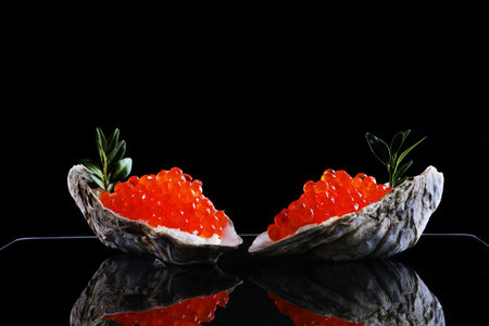 Red caviar in oyster shells. Serving snacks with red caviar and cheese. Salmon roe.A useful omega. Black background. Space for copying.の写真素材