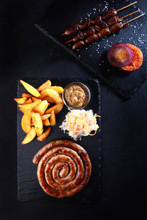 Grilled sausages. French fries and sauerkraut on the table. Appetizer for beer. Grilled sausages. A classic German beer snack. Photos for the menu. Vertical photo.Flat lay.Top view.の写真素材