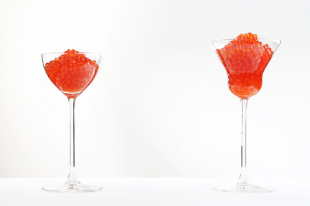 Red salmon caviar.Red caviar in tall glass wine glasses. White background. Isolated object. Copy space.の写真素材