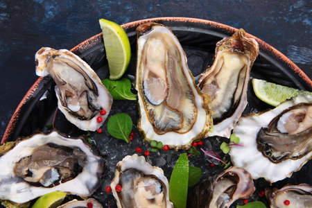 Oysters with lime on a round plate. Oysters are lying on ice. Oyster season. An open oyster shell.Flat lay.Top view. Flat lay.の写真素材