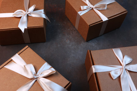 Cardboard boxes on a dark background. Delivery of gifts for the holiday. The cardboard holiday box is tied with a ribbon. Festive packaging. With space to copy.の写真素材