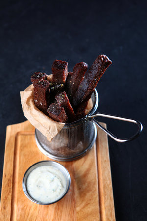 Bread croutons. Fried slices of rye bread. Appetizer for beer from bread. Photos for bars or restaurants. Black background. Vertical photo.の写真素材