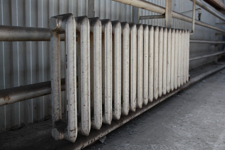 Pipes and a white heating radiator heat the room. An old cast-iron battery. The battery is painted white.Out of focus.Selective focus.Copy space.の写真素材