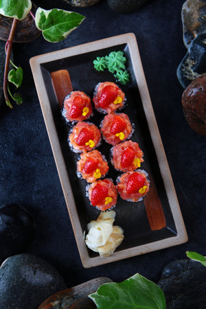 Japanese sushi. Traditional Japanese cuisine. Rolls with tobiko caviar and decorated with a slice of strawberries.Exquisite presentation.White ginger. Vertical photo.の写真素材