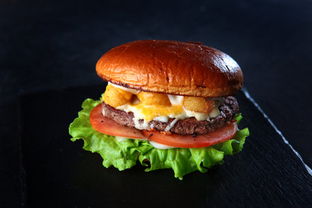 Homemade hamburger or burger with fresh vegetables. Burger with tomatoes on a black background.A quick snack. The concept of fast food.の写真素材
