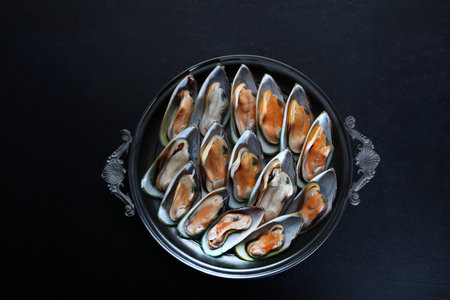 Mussels on a platter. Large mussels. Seafood on a dark background. Flat lay. Top view. Copy space.の写真素材