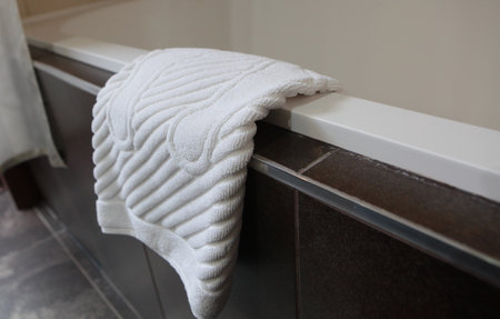 A foot towel in the bathroom. A foot towel hangs on the edge of the tub.Bathroom.The concept of comfort and cleanliness.の写真素材