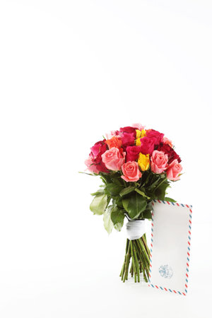 Bouquet of roses on a white background. An envelope with a letter. Vertical photo. Isolated object. The concept of the holiday.の写真素材