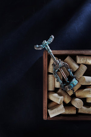 An antique corkscrew and a wooden box with wine stoppers. Natural cork. The concept of winemaking. Flat lay. Top view. Copy space.の写真素材