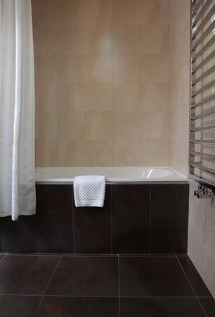 A foot towel in the bathroom. A foot towel hangs on the edge of the tub. Bathroom. Vertical photo.The concept of comfort and cleanliness.の写真素材
