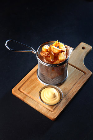 French fries in a rustic way with sauce. Wooden board. Dark background. Vertical photo. Copy space.の写真素材
