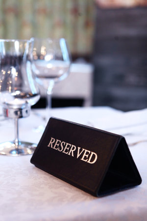 Table reservation in the restaurant. Booking a table in a restaurant.There is a sign on the table that says Reserve. Vertical photo.の写真素材