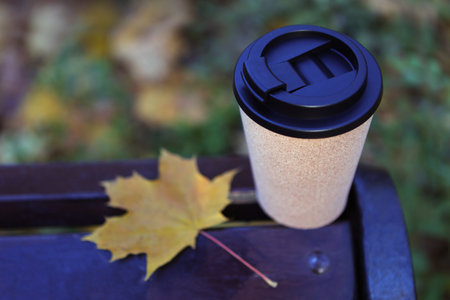Autumn Park. Travel mug with a lid for a hot drink.A cup of coffee with lid on a park bench. Hot drink. Notepad for drawings or notes. Weekend. Recreation in the park.の写真素材