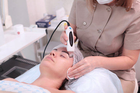 Beautiful woman receiving ultrasound cavitation facial peeling. Cosmetology and facial skin...