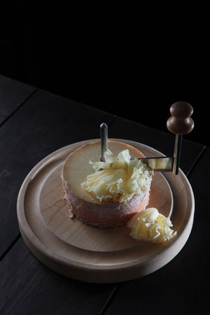 Slice the tete des Moines cheese with a girolle knife. A kind of Swiss semi-hard cheese. A special cheese knife. Vertical photo.の写真素材
