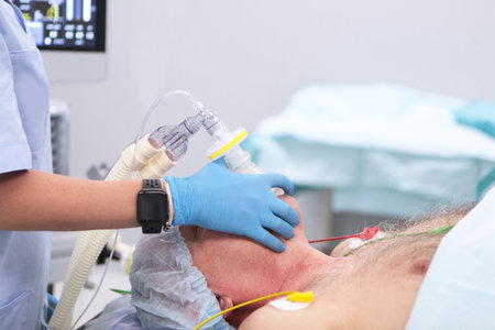 An elderly man is undergoing surgery. Preparation for anesthesia and surgical intervention of an elderly man. Modern medicine. The doctors hands are in protective gloves.の写真素材