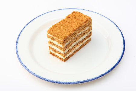 A piece of delicious layered honey cake, highlighted on a white background. Piece of honey cake on a...