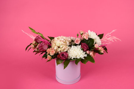 Bouquet of flowers on a pink background. A bouquet in a pink cardboard box. Box with a bouquet of flowers. Copy space.の写真素材