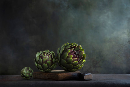 Artichokes on a wooden board. Dark background. Space for copying.の写真素材