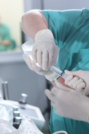 Preparation of the injection. Syringe in hands of doctors. Operating unit. Unrecognizable persons. Modern surgery. Vertical photo.の写真素材