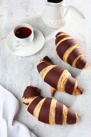 Delicious freshly baked chocolate croissants on a light background. French breakfast. Delicious pastries in close-up. Confectionery products.の写真素材