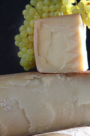 A bunch of grapes and cheeses. Large chunks of hard cheese. Hard cheeses.の写真素材