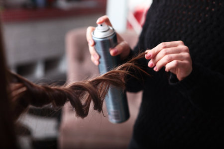 Hairstyle with curls. A close-up curl. A hairdresser in a beauty salon makes a womans hair with curls using hairspray. The concept of beauty.の写真素材