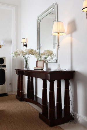 Stylish interior with console table and rectangular mirror. Modern design. A vase with orchids on...
