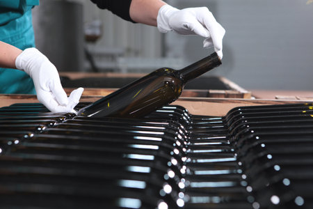 Wine storage. Young wine in bottles is stacked in stacks. Hands in white gloves.の写真素材