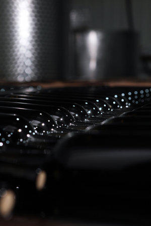 Wine bottles are stacked for storage. Bottles lie in rows. Young wine. Craft winery. Selective...