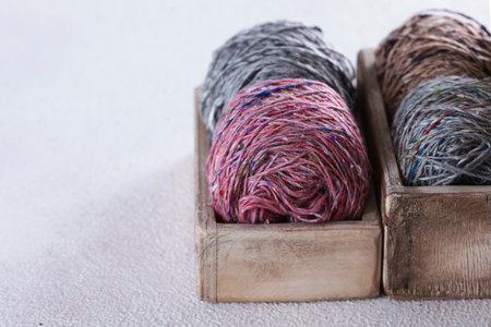 Different types of tweed yarn. Balls of yarn in box. Classic wool yarn for warm clothes. Light background. Hobby concept. Handmade work. Copy spaceの写真素材