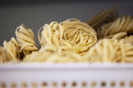 Classic Italian pasta is in the basket. The freshly made pasta curls up into a spiral and resembles a birds nest. Durum flour. Healthy eating. Handmade work.の写真素材