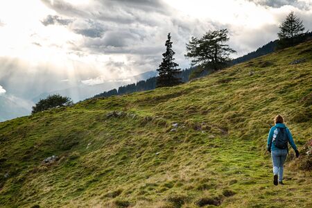 Lonely girl walking to the sunset in Austria mountainsの写真素材