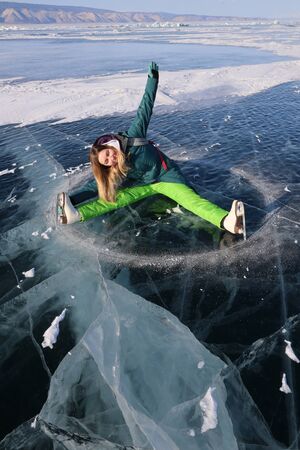 Girl with skates lying on ice of Baikal lakeの写真素材