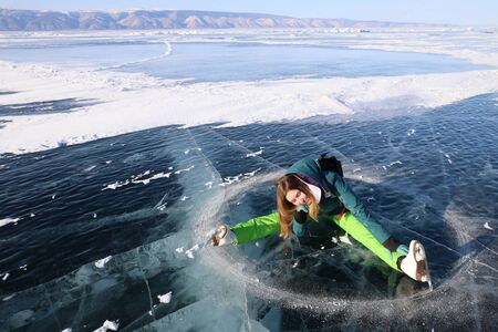 Girl with skates lying on ice of Baikal lakeの写真素材