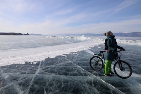 Girl with a bicycle in iced Baikal lakeの写真素材