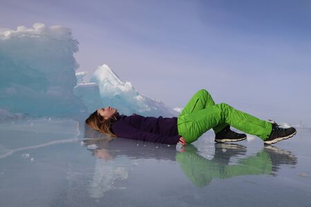 Girl lying on ice of Baikal lakeの写真素材