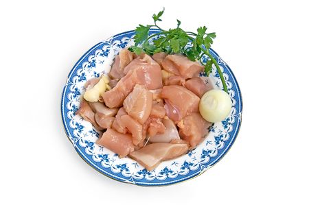 Chicken fillet, cut into large chunks on a plate with onions and parsleyの写真素材