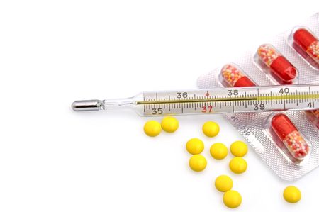 Thermometer with the yellow pills in bulk and red-white capsules in a package on a white backgroundの写真素材