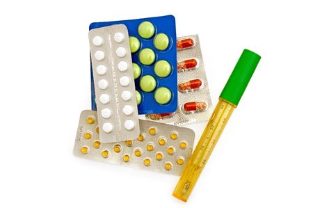 Thermometer in a case with multi-colored capsules and tablets in containers on a white backgroundの写真素材