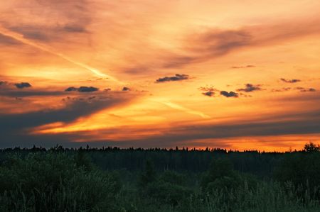 A beautiful sunrise, clouds, painted in red, orange, trees, forestの写真素材