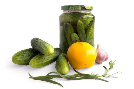 Jar of pickled cucumbers, fresh green cucumbers, yellow peppers, garlic and tarragon sprig in isolation on a white backgroundの写真素材