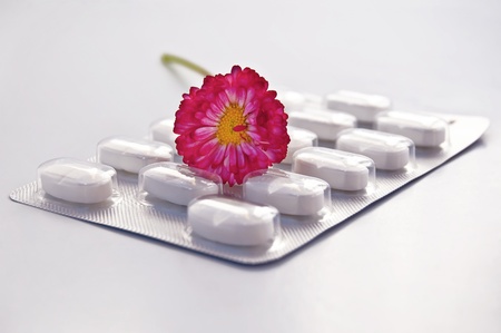 White round pill in a package with daisy isolated on gray backgroundの写真素材