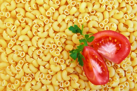 Texture units of the yellow pasta with two slices of tomato and a sprig of parsleyの写真素材