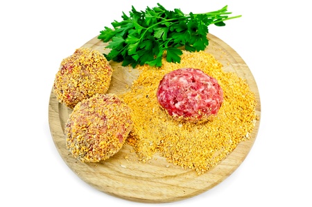 Three homemade meatballs, bread crumbs, a bunch of green parsley on a circular wooden board isolated...