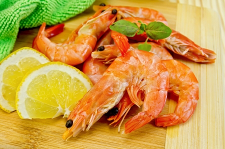 Shrimp with lemon, basil and green cloth on a wooden boardの写真素材